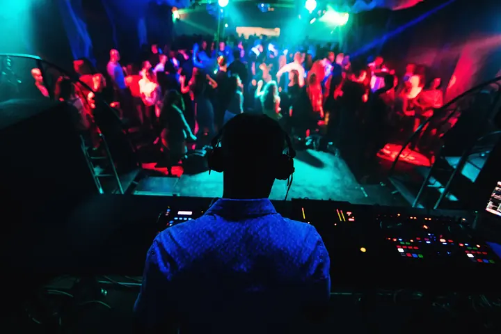 The view from behind the decks over a dancing crowd